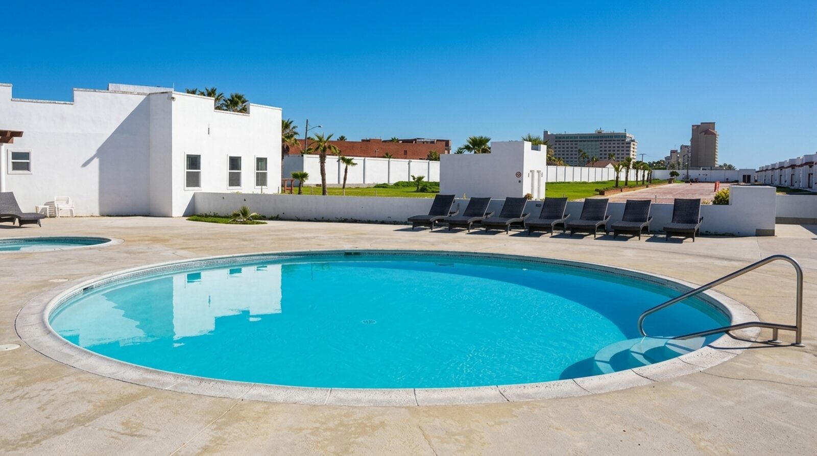 La alberca del complejo, con las villas blancas y las torres de la costa al fondo.